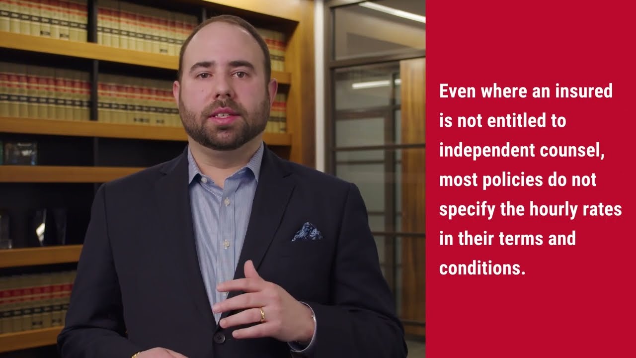 Man in a suit speaking about legal insurance policies, with law books in the background, emphasizing the importance of video marketing for law firms.