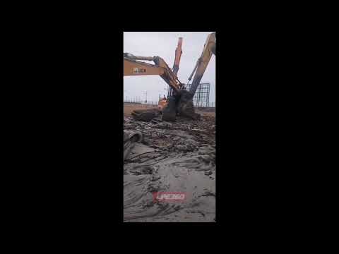 Excavator getting pulled out of mud
