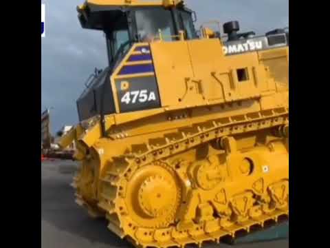 new & old komatsu d475 a line of bulldozer unloading and loading onto a trailor