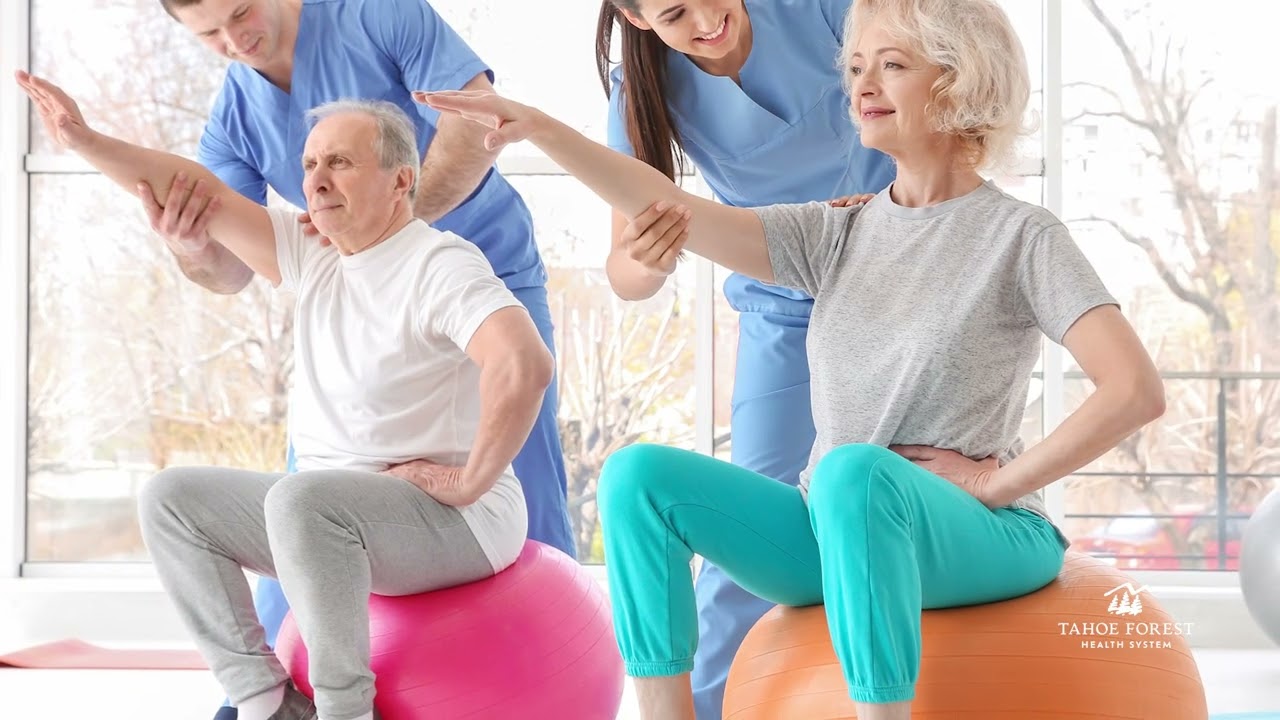 Older couple sitting on exercise balls with two physical therapists assisting them