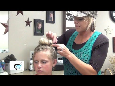Hair stylist creating a high messy bun on a young girl, showcasing a practical hairstyle suitable for active days, with a focus on height and stability.