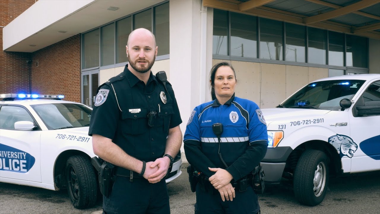 AU police officers stand in front of patrol car