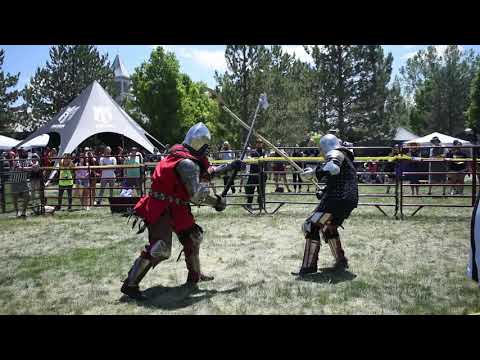 Medieval Knight breaks opponents helmet during full contact armored combat and knocks him down