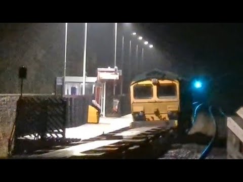 Freight train appears out of the mist, rain and darkness at Slawit