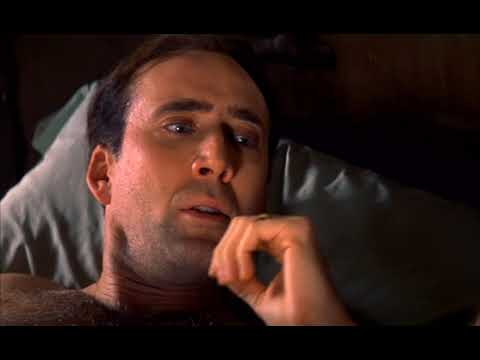 Universal’s The Family Man trailer frame: Nicolas Cage and Téa Leoni in a warmly lit kitchen, Christmas glow beyond