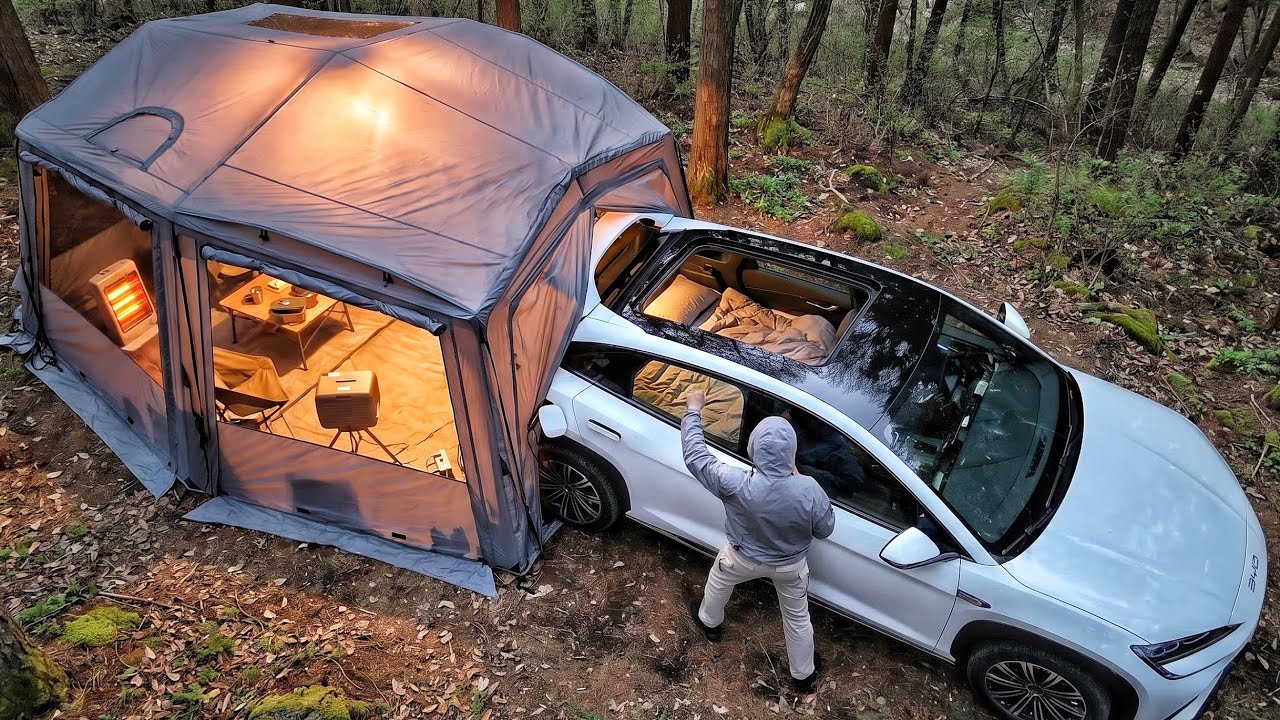 BYD Sealion 7 parked at the edge of an Arbor Outdoor HEXONA tent in a quiet forest at night with warm ambient lighting