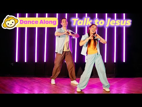 Two young dancers perform a joyful dance on a stage with purple neon vertical lights and 'Dance Along'/'Talk to Jesus' banners.