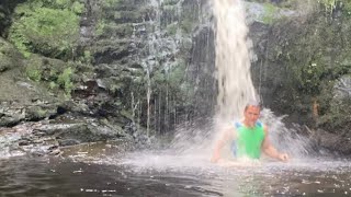 Waterfall shower in mountain stream cooling on trail run wet sports clothes wildswimming