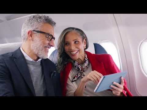 Mature couple on airplane using a tablet.