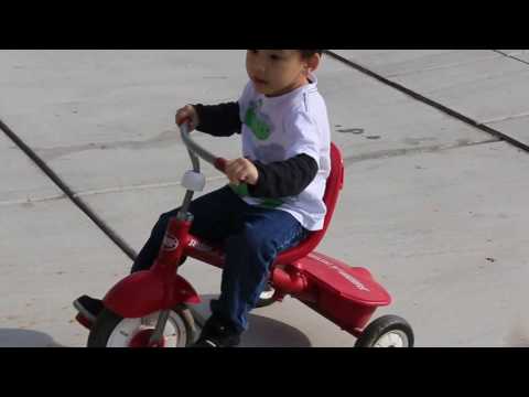 Kid learning & playing riding red radio flyer tricycle