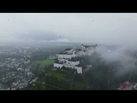 Aerial views reveal fog enveloping Salzburg, shrouding the city and Hohensalzburg Fortress. The