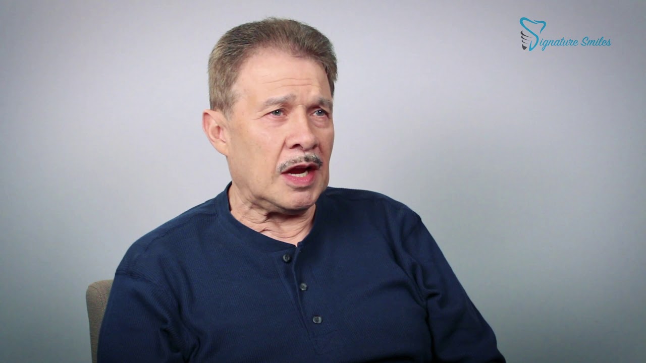 Man in dark colored shirt talking in dental office