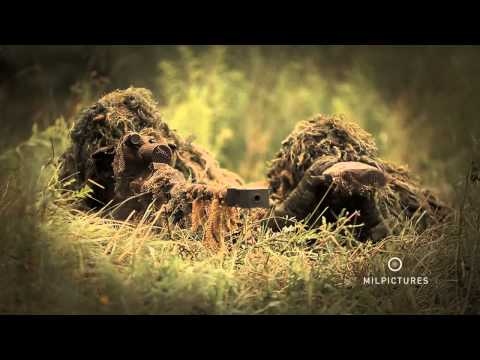 Sniper with ghillie suit shooting a heavy anti materiel sniper rifle