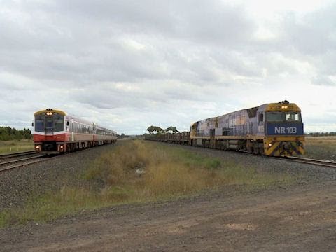 Passenger Train and Long Freight Train pace each other towards Railroad Level Crossing - PoathTV