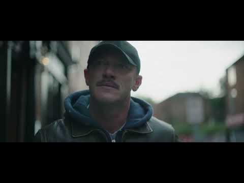 Trailer close-up: a stare through a cracked windshield as sirens bleed into the mix