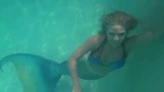 Trina Mason the mermaid holding onto a pool railin