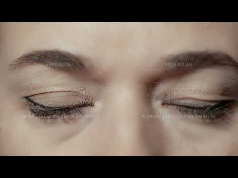 Close-up eye-portrait of a young caucasian woman who is watching seriously and directly into camera