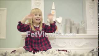 Small girl in red dress sits on a carpet and claps hands