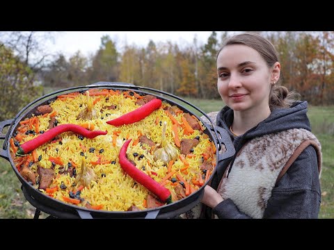 Ukrainian woman cooks tradition Pilaf on an open fire in the village