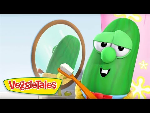Green VeggieTales cucumber character brushing teeth with an orange toothbrush in front of a round mirror in a bright bathroom.