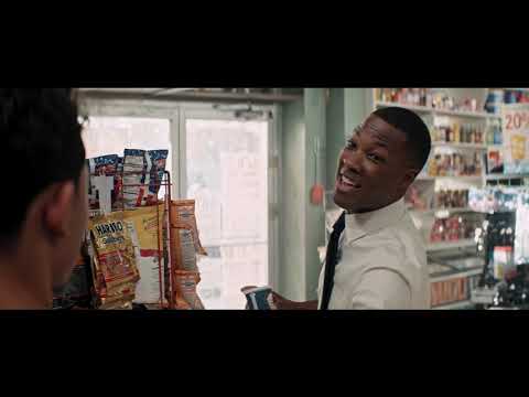 In the Heights (2021) official trailer still: Usnavi outside the bodega with Washington Heights block in motion