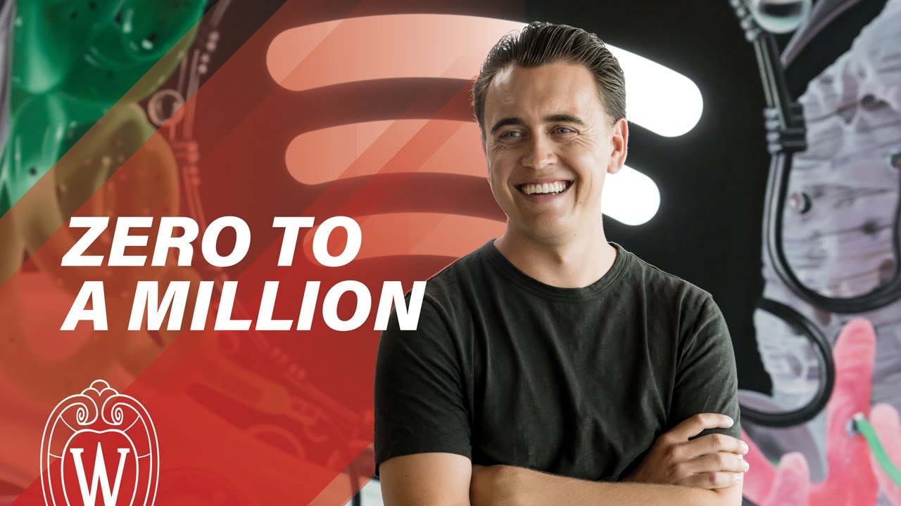 Young man in black t-shirt smiling in front of Spotify logo in the Spotify office; text says "Zero to a million".