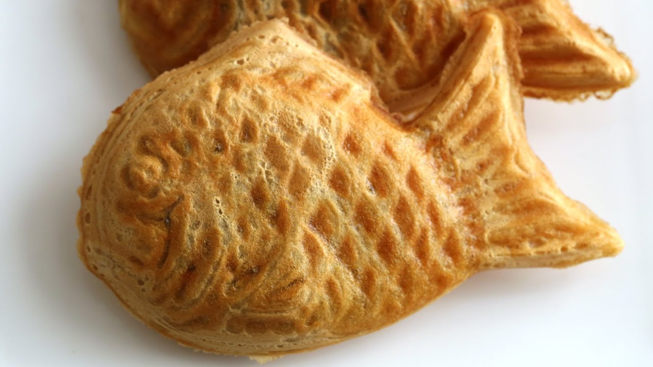 Three Korean bungeoppang fish-shaped pastries golden brown with crispy edges arranged on parchment paper showing the detailed fish scale pattern