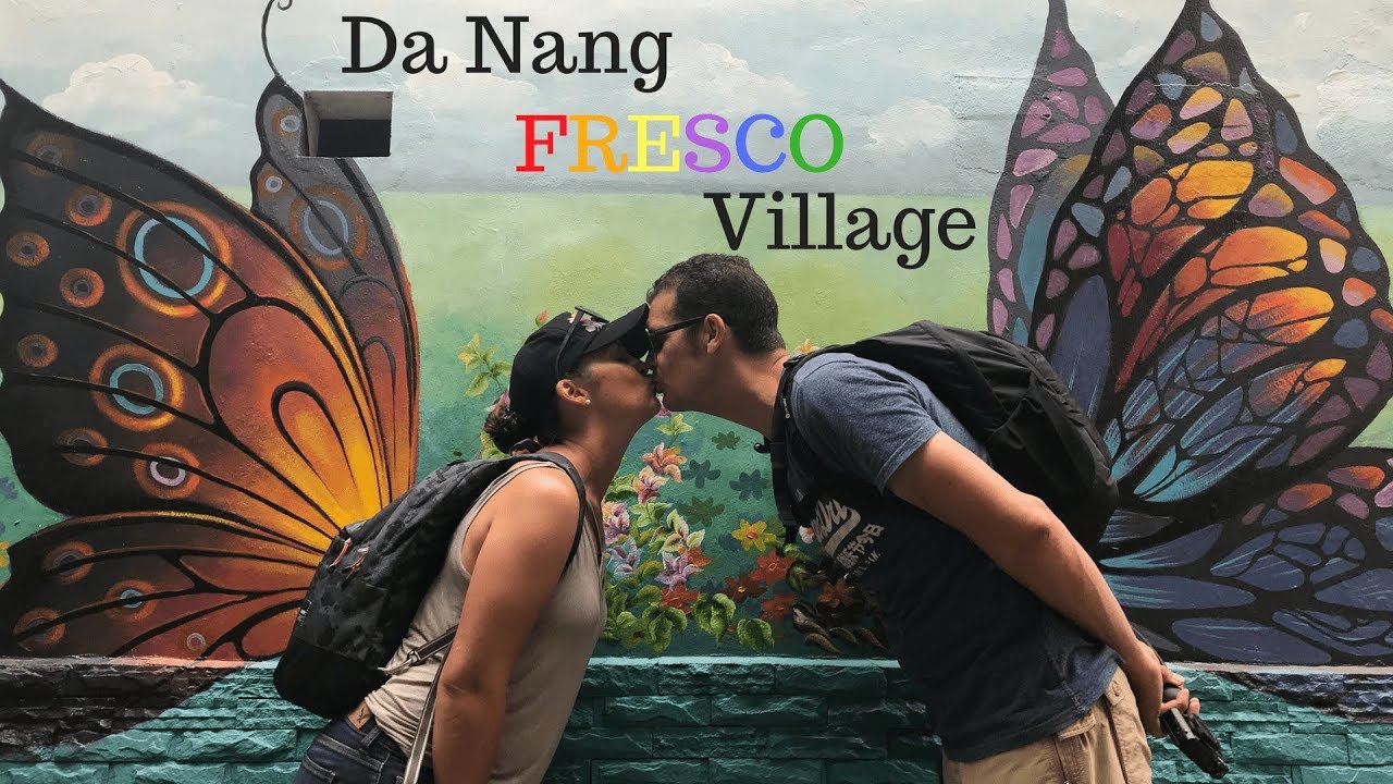 Tourists explore the vibrant Fresco Village in Da Nang, admiring its colorful murals that depict local life and culture.