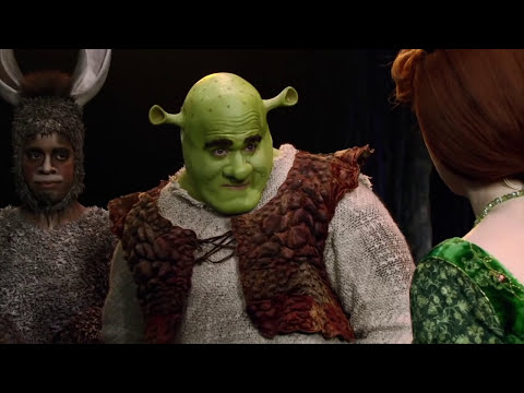 Trailer frame of Donkey hyping up Shrek with a groove, staged with fairy-tale creatures in the background