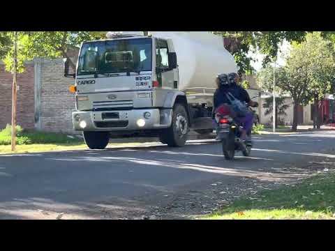 A dirt road sprinkler truck passes