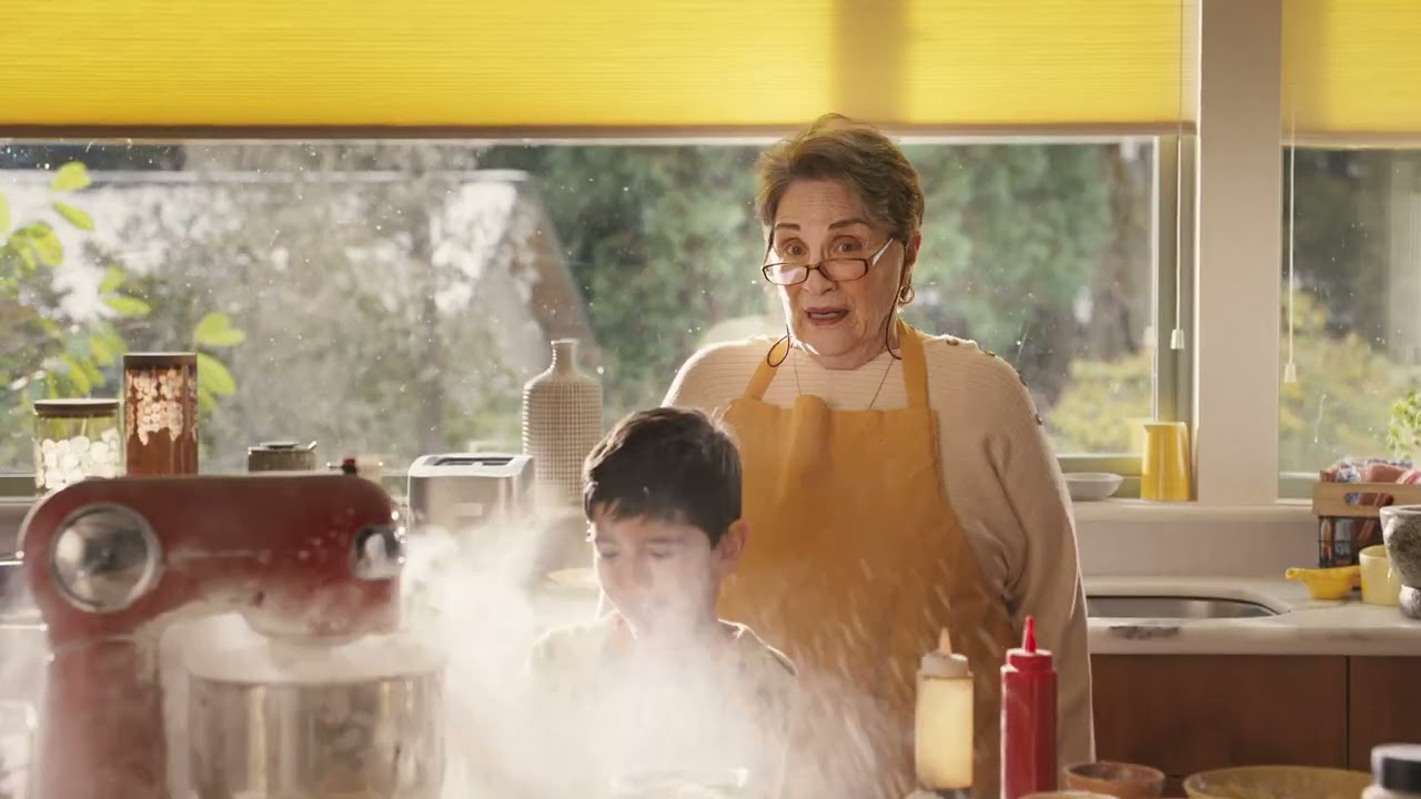 A surprised woman looks on at a young boy making a mess in a kitchen