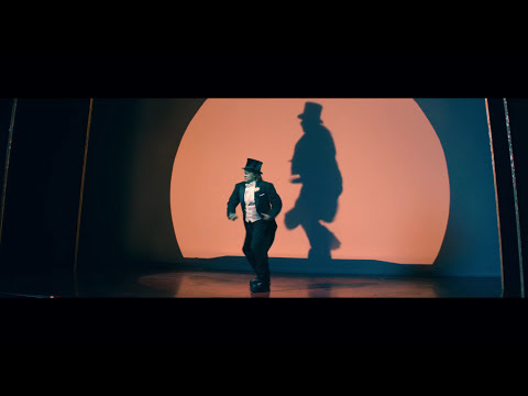 Trailer still: top hats and canes teased in a flash of green light