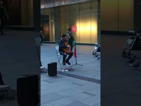 A guitarist playing "Speak softly love" on Market St, Australia