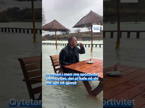 Qytetari i merr me sportivitet përmbytjet, del pi kafe në shi me ujin në gjunjë