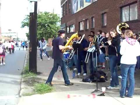 Man on street corner dances with the John Carroll University Pep Band