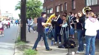 Man on street corner dances with the John Carroll University Pep Band