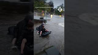 Boys use air mattress as river raft in Storm Babet floodwaters