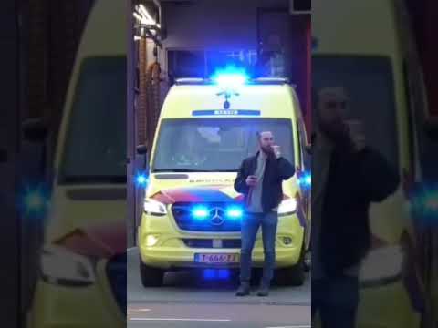 Man blijft voor Ambulance stil staan die met sirene onderweg is naar een Melding tijdens Koningsdag