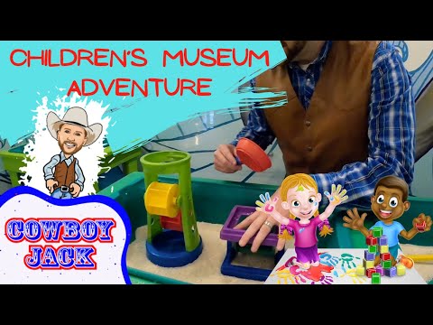 Bright thumbnail for a children's museum adventure: sand play station, a man in a brown vest, cartoon characters, and the text 'Cowboy Jack'.