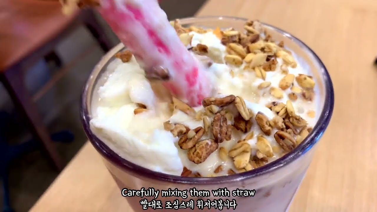 A Gong Cha bubble tea cup with milk tea and tapioca pearls held up in front of a Korean storefront in Seoul