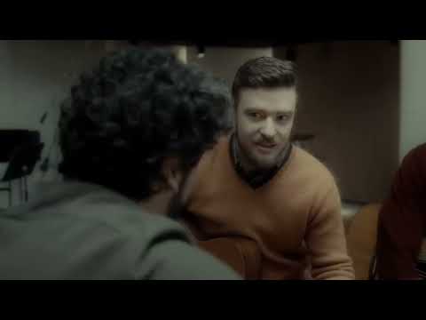Inside Llewyn Davis official trailer frame: Llewyn on the Gaslight stage under a lone spotlight, guitar in hand