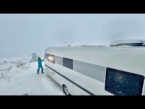Camping in einem komfortablen Wohnwagen während eines eisigen Schneesturms.