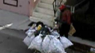 Bum in the alley pilfering from the city recycle bin