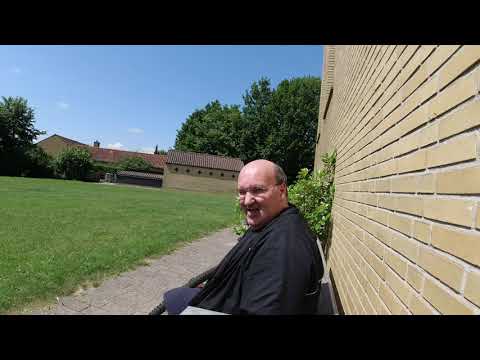 MongoTV_6601 - SIDDER OG KOGER I SOLEN PÅ EN BÆNK BAG KIRKEN OG SPISER CHIPS