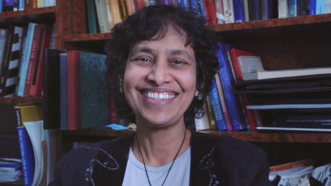 Asha Rao smiling, in front of a bookcase