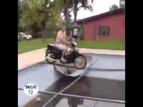Hombre en moto pasa sobre una pileta de agua sucia sobre una reja