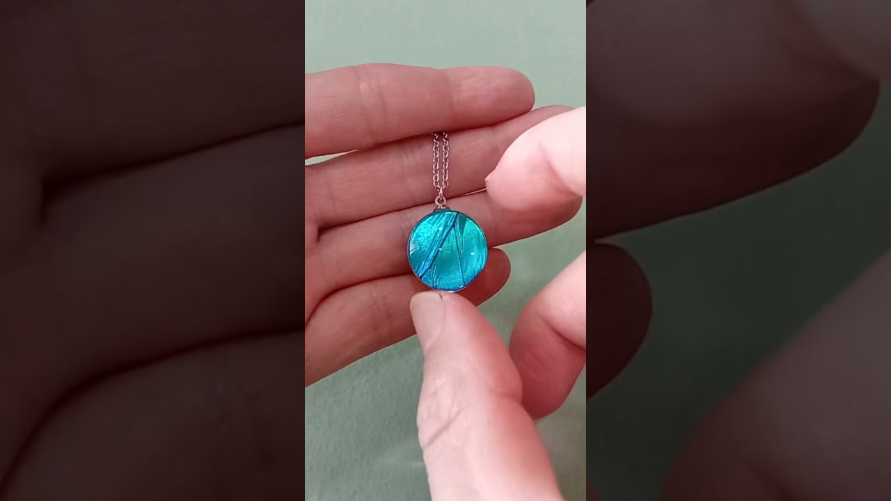 20mm Artisan Blue Morpho menelaus real butterfly wing necklace under glass lens reflecting iridescent blue light