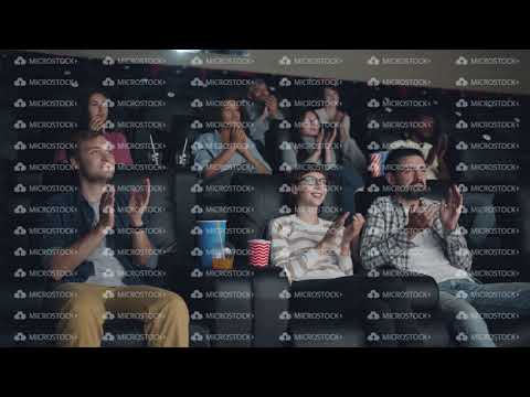 Excited young people clapping hands sitting in cinema expressing admiration