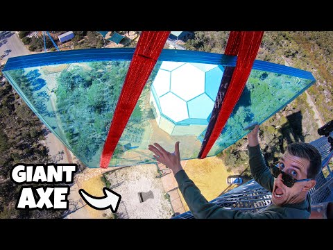 YouTube thumbnail showing a man in sunglasses on a glass walkway high above ground, with a large red axe between the glass panels and bold 'GIANT AXE' text in the corner.