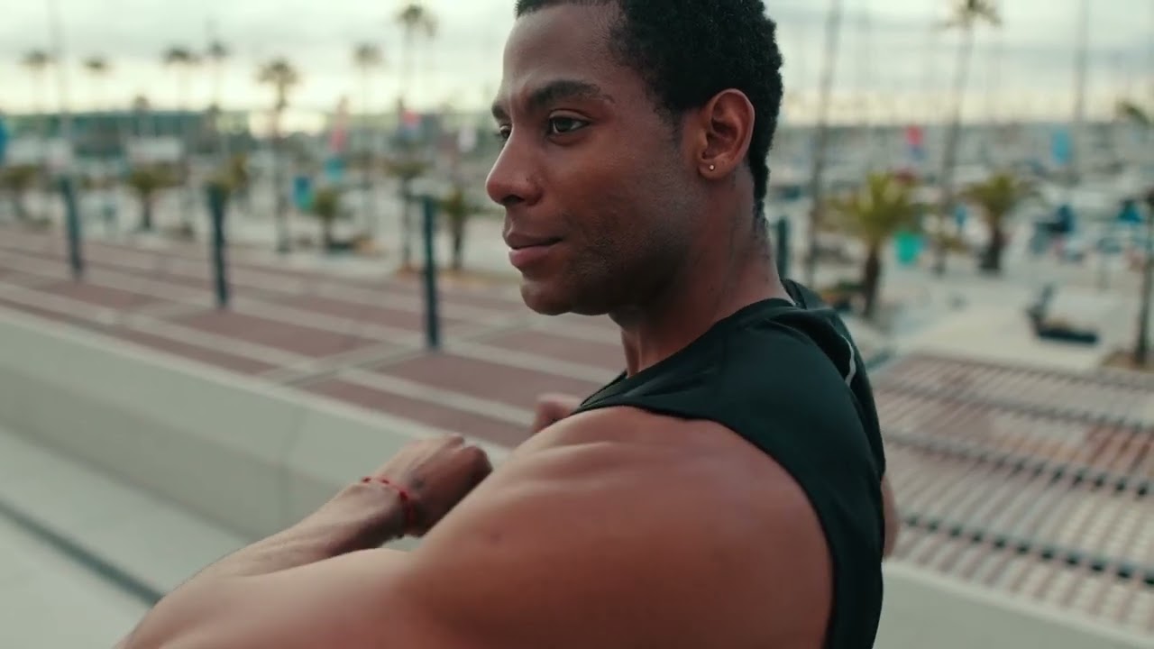 Male athlete stretching at an athletic training field.